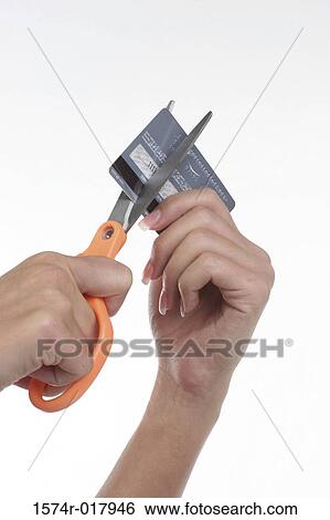 Stock Photograph - Close-up of a person's hand cutting a credit card with a pair of scissors. Fotosearch