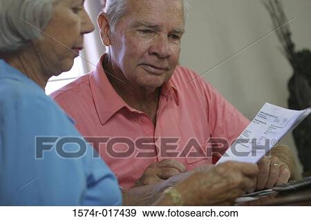Close-up of a senior couple reading a bill View Large Photo Image Stock Photo - Close-up of a senior couple reading a bill. Fotosearch