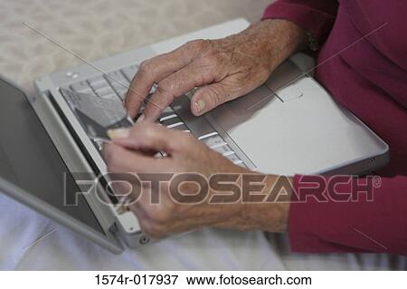 Close-up of a woman's hands using a laptop holding a credit card View Large Photo Image Stock Photo - Close-up of a woman's hands using a laptop holding a credit card. Fotosearch