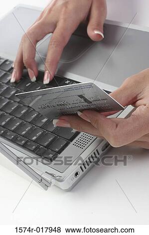 Close-up of a woman's hands using a laptop holding a credit card View Large Photo Image Stock Photo - Close-up of a woman's hands using a laptop holding a credit card. Fotosearch