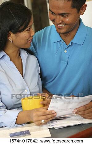 Stock Image - Close-up of a young couple holding a bill. Fotosearch