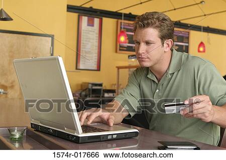 Close-up of a young man using a laptop and holding a credit card for online shopping View Large Photo Image Stock Photograph - Close-up of a young man using a laptop and holding a credit card for online shopping. Fotosearch