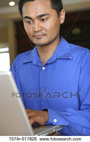 Close-up of a young man using a laptop View Large Photo Image Stock Photograph - Close-up of a young man using a laptop. Fotosearch