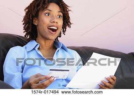 Close-up of a young woman holding a credit card and a bill View Large Photo Image Picture - Close-up of a young woman holding a credit card and a bill. Fotosearch