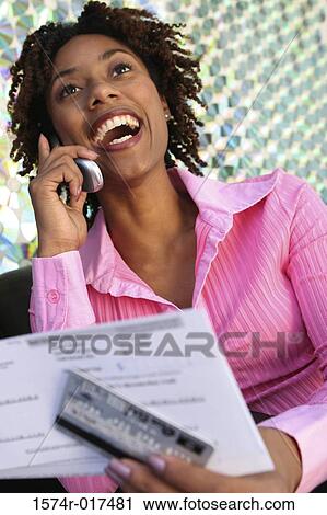 Close-up of a young woman holding a bill using a mobile phone View Large Photo Image Stock Image - Close-up of a young woman holding a bill using a mobile phone. Fotosearch
