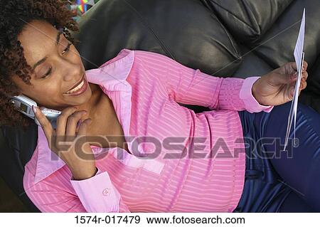 Close-up of a young woman holding a bill using a mobile phone View Large Photo Image Stock Photo - Close-up of a young woman holding a bill using a mobile phone. Fotosearch