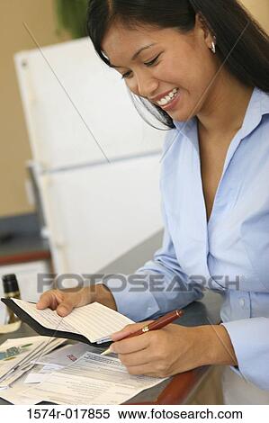 Close-up of a young woman holding a checkbook View Large Photo Image Stock Photography - Close-up of a young woman holding a checkbook. Fotosearch