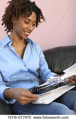 Stock Image - Close-up of a young woman reading bills. Fotosearch