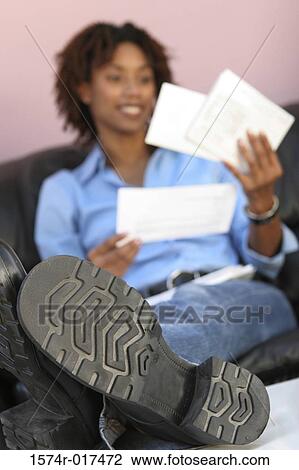 Stock Image - Close-up of a young woman reading bills. Fotosearch