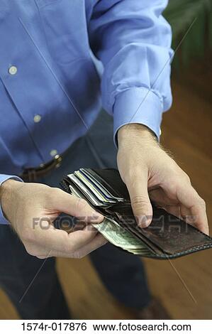 Stock Photograph - High angle view of a mid adult man holding a wallet. Fotosearch