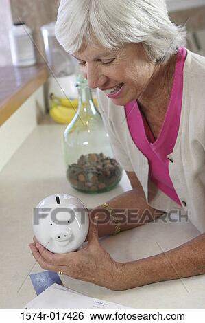 High angle view of a senior woman holding a piggy bank View Large Photo Image Stock Photograph - High angle view of a senior woman holding a piggy bank. Fotosearch