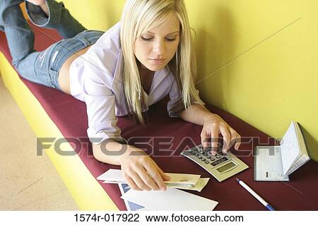 High angle view of a young woman lying on a bench with bills and a calculator in front of her View Large Photo Image Stock Image - High angle view of a young woman lying on a bench with bills and a calculator in front of her. Fotosearch