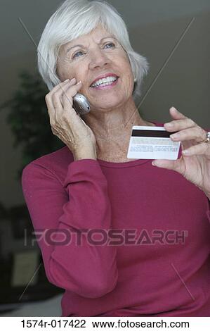 Low angle view of a senior woman talking on a mobile phone holding a credit card View Large Photo Image Stock Image - Low angle view of a senior woman talking on a mobile phone holding a credit card. Fotosearch