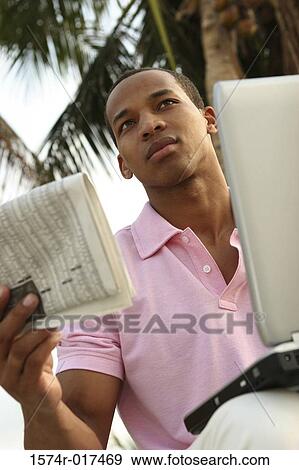 Stock Photo - Low angle view of a young man holding a newspaper. Fotosearch