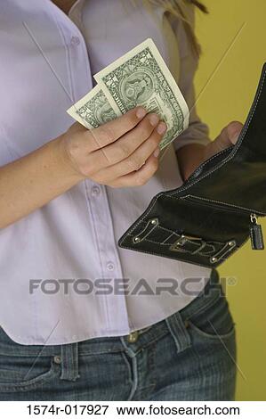 Mid section view of a young woman holding dollar bills and a purse View Large Photo Image Stock Photo - Mid section view of a young woman holding dollar bills and a purse. Fotosearch