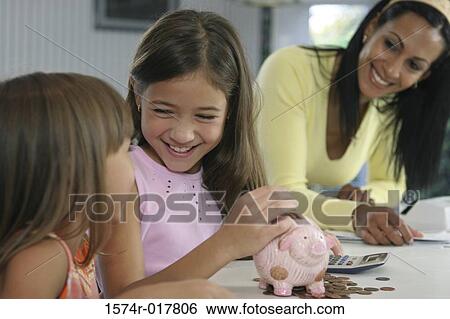 Stock Photograph - Mother with her two daughters smiling near a piggy bank. Fotosearch