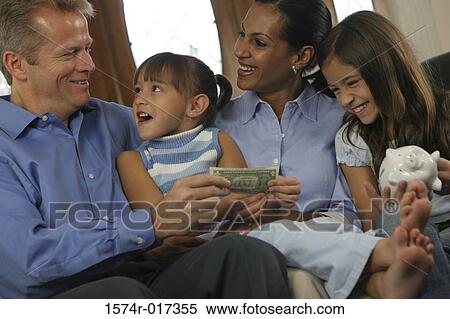Stock Photography - Parents sitting with their two daughters holding money. Fotosearch