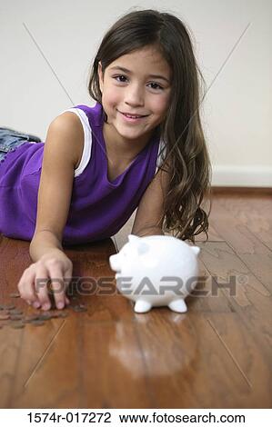 Portrait of a girl lying on the floor with a piggy bank in front of her View Large Photo Image Stock Image - Portrait of a girl lying on the floor with a piggy bank in front of her. Fotosearch