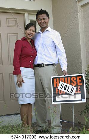 Portrait of a young couple standing outside a house holding a sold sign View Large Photo Image Stock Image - Portrait of a young couple standing outside a house holding a sold sign. Fotosearch