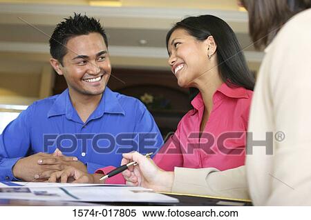 Stock Photography - Real estate agent talking to a young couple. Fotosearch
