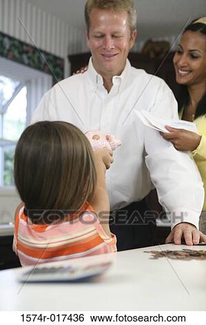 Stock Photograph - Rear view of a daughter showing a piggy bank to her parents. Fotosearch