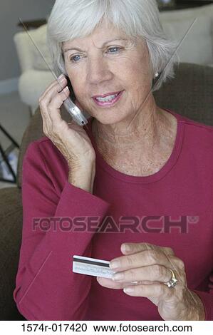 Senior woman talking on a mobile phone holding a credit card View Large Photo Image Stock Image - Senior woman talking on a mobile phone holding a credit card. Fotosearch