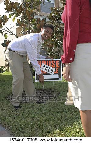 Stock Photo - Young man holding a sold sign. Fotosearch