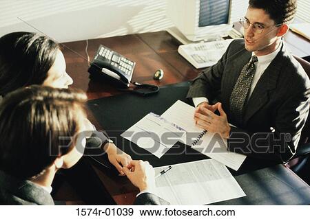 Business executives sitting across a desk View Large Photo Image Stock Photo - Business executives sitting across a desk. Fotosearch