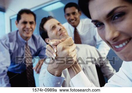 Stock Image - Businessman and a businesswoman arm wrestling. Fotosearch