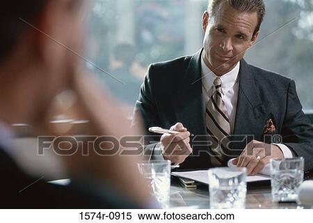 Stock Photography - Businessman seated at a table signing a document. Fotosearch
