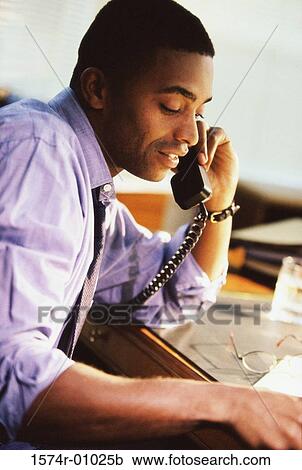 Businessman talking on a landline telephone on the desk View Large Photo Image Stock Image - Businessman talking on a landline telephone on the desk. Fotosearch