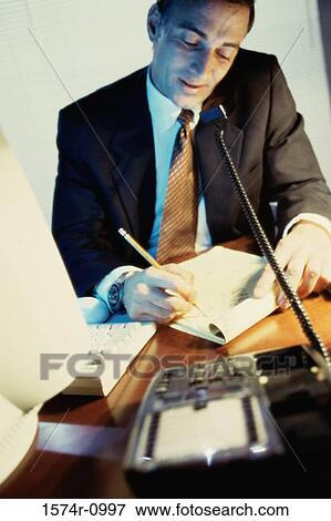 Businessman talking on a landline telephone on the desk View Large Photo Image Stock Photo - Businessman talking on a landline telephone on the desk. Fotosearch