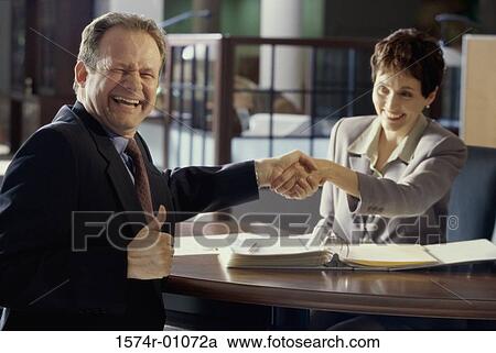 Businesswoman shaking hands with a businessman in an office View Large Photo Image Stock Image - Businesswoman shaking hands with a businessman in an office. Fotosearch