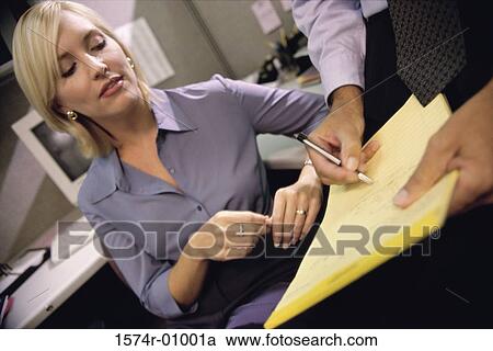 Stock Image - Close-up of a young businesswoman reading a document in a person's hands. Fotosearch