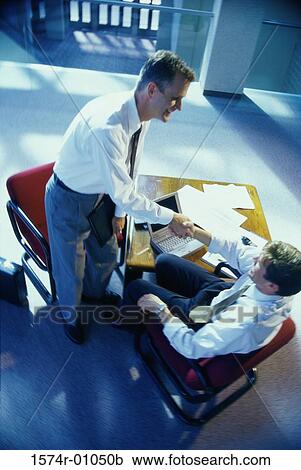 Stock Image - High angle view of two businessmen shaking hands. Fotosearch