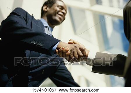 Low angle view of two businessmen shaking hands View Large Photo Image Stock Photo - Low angle view of two businessmen shaking hands. Fotosearch