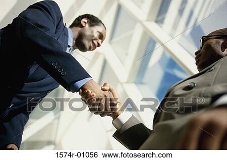 Stock Photograph - Low angle view of two businessmen shaking hands. Fotosearch