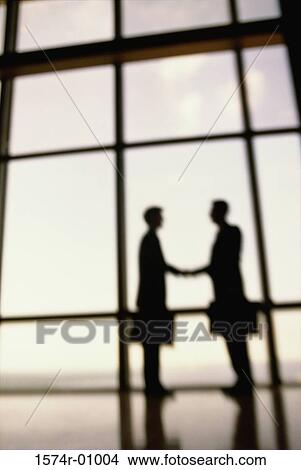 Picture - Silhouette of two businessmen shaking hands. Fotosearch