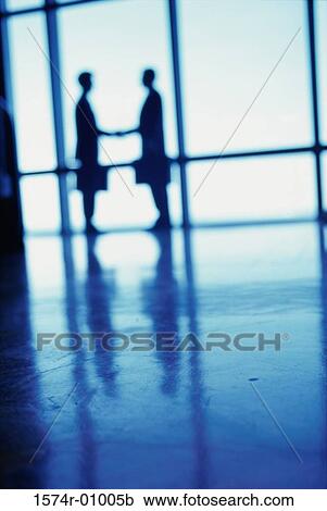Stock Image - Silhouette of two businessmen shaking hands. Fotosearch