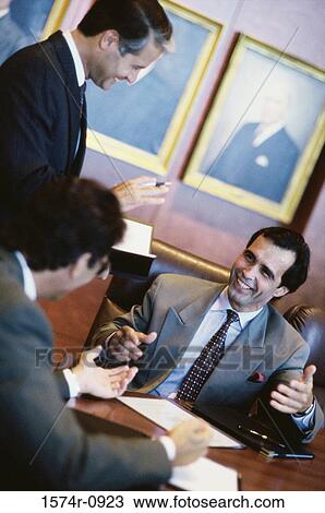 Stock Image - Three businessmen discussing in an office. Fotosearch