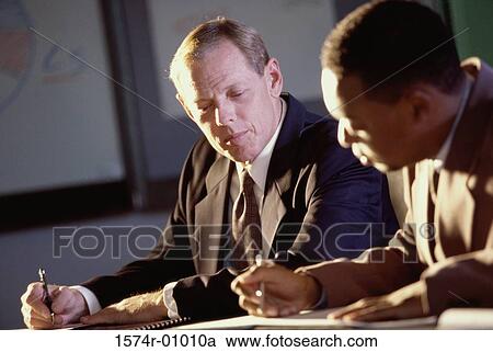 Stock Image - Two businessmen signing documents. Fotosearch