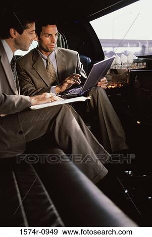 Stock Photo - Two businessmen using a laptop in a car. Fotosearch