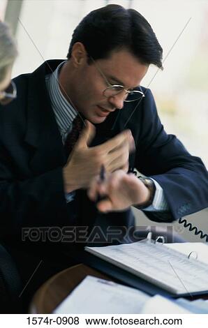 Young businessman talking on a landline telephone View Large Photo Image Stock Photo - Young businessman talking on a landline telephone. Fotosearch