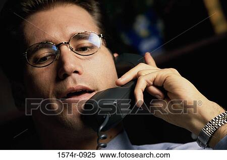 Stock Photography - Young businessman talking on a landline telephone. Fotosearch