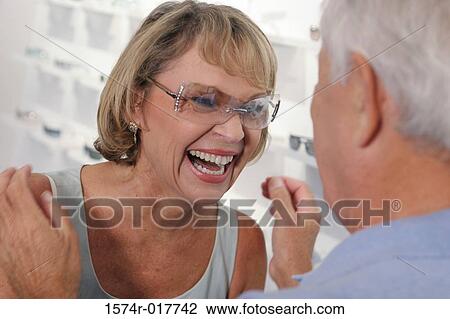 Stock Image - Close-up of a senior woman trying on sunglasses in a store. Fotosearch