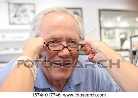 Close-up of a woman's hands putting eyeglasses on a senior man View Large Photo Image Stock Photograph - Close-up of a woman's hands putting eyeglasses on a senior man. Fotosearch