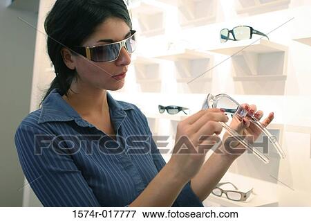 Stock Photo - Close-up of a young woman selecting sunglasses in a store. Fotosearch