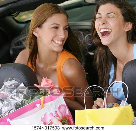 Stock Image - Close-up of two young women smiling in a car. Fotosearch