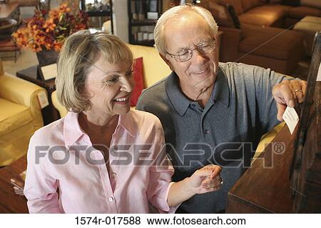 Stock Photo - High angle view of a senior couple looking at a price tag in a furniture store. Fotosearch