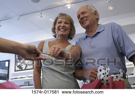 Low angle view of a senior couple handing a credit card to a person View Large Photo Image Stock Image - Low angle view of a senior couple handing a credit card to a person. Fotosearch